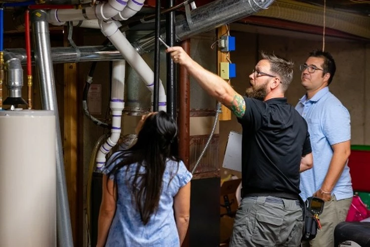 Picture of a Home Inspector reviewing plumbing pipes with client