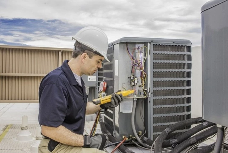 Picture of an HVAC Contractor taking electrical readings from the AC unit