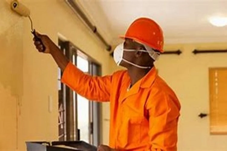 Picture of a Painting Contractor painting an interior wall of the home a golden yellow