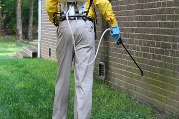 Picture of a Pest Contractor applying insecticide at the exterior of the home to prevent indoor infestations
