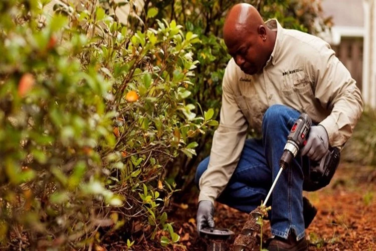 Image of a Pest Contractor installing a termite bait startion at the exterior of the home
