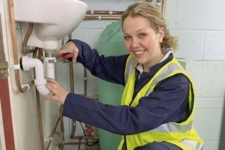 Picture of a Plumbing Contractor working on a pipe under the bathroom sink
