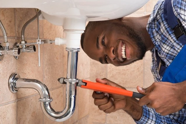 Picture of a female Plumbing Contractor working on a pipe under a water fountain